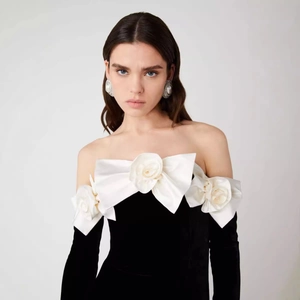 Off-shoulder black velvet gown with large white satin rose and slim fishtail silhouette