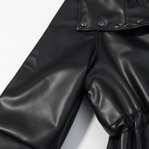 Detailed close-up of premium black leather jacket with metal button and stitching texture