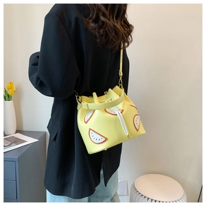 Detail of yellow fruit-pattern bucket bag with white drawstring and gold hardware accents