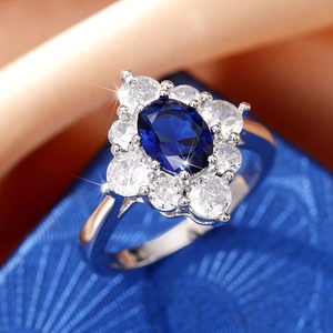 Luxuriöser eiförmiger blauer Zirkonring mit Halo-Fassung auf Satin-Hintergrund