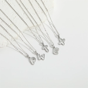 Detailed macro shot of silver letter pendants with honeycomb texture on a white stone