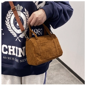 Close-up of a brown corduroy Boston crossbody bag worn by a model in a minimalist setting