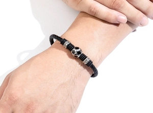 Close-up of a woven black leather bracelet with a soccer ball bead and silver accents