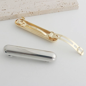 Detail of gold and silver metal spring hair clips showing the internal mechanism