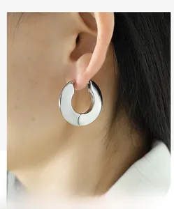 Macro shot of silver wide hoop earrings with a polished mirror finish on a female model