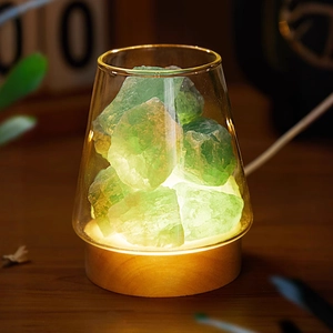 Close-up of green crystal stone lamp with a wooden base and warm glowing light effect