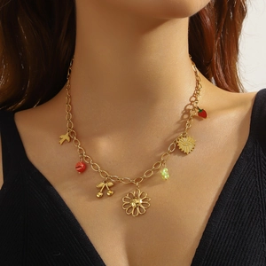 Gold chain necklace with floral, sun and fruit pendants worn by model on neck