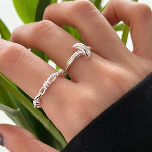 Minimalist 925 sterling silver woven chain and knot rings set on a nature-inspired background