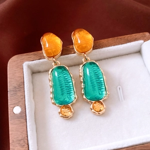 Detail of vintage oval resin earrings in orange and green with gold metal frame edges