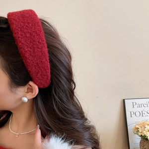 Detail of red plush headband on model with elegant pearl earrings in a French chic setting