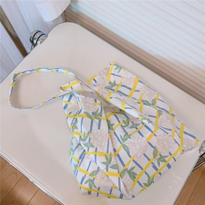 Detailed overhead shot of a cotton tote bag with floral patterns and yellow plaid straps
