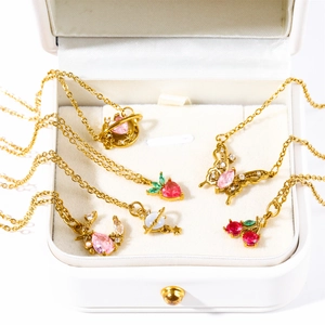 Detail view of assorted cherry, butterfly, and planet pendants in a white jewelry box