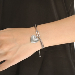 Detail of silver heart charm bracelet with textured rays and mixed chain styles