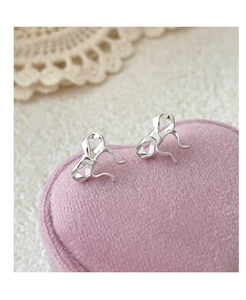 Close-up of silver S999 bow earrings displayed on a pink velvet heart-shaped box