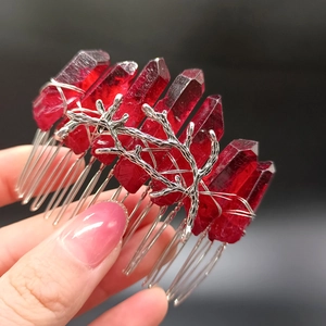Detailaufnahme von rotem Kristall-Haarkamm mit silbernen Zweigen in der Hand gehalten