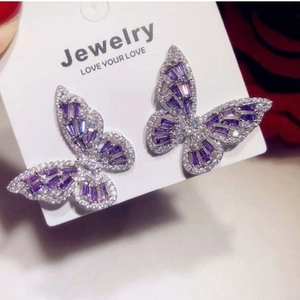 Exquisite silver-tone hollow butterfly earrings with purple zircons on a jewelry card