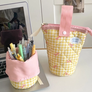 Detail of yellow checkered quilted pencil case with red bow patterns and pink handle