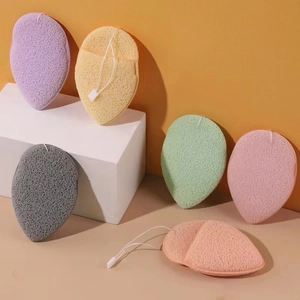 Set of 6 colorful teardrop facial sponges with hanging ropes on minimalist orange backdrop