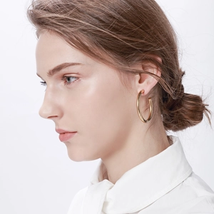 Close-up of oversized gold-plated C-shaped stainless steel hoop earrings on model