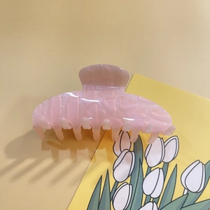 Detailed view of pink translucent acrylic hair claw clip on a decorative tulip card