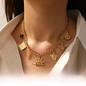 Detail of gold stainless steel necklace with tiger eye and seashell charms for women