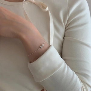 Detailed view of an elegant 925 silver bow bracelet on a model's wrist with soft lighting