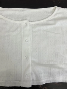 Vue détaillée de la texture du tricot pointelle blanc avec des boutons assortis