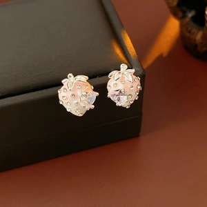 Macro shot of strawberry earrings with pink enamel, heart crystal, and silver leaves