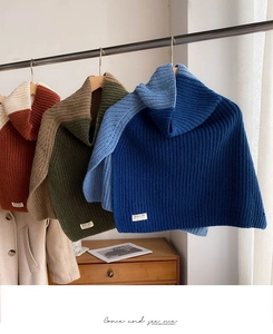 Detailed knit texture of color-block turtleneck ponchos hanging on a display rack