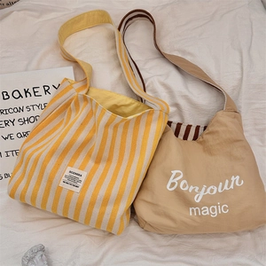 Dettaglio di borse tote in tela a righe e borse a tracolla kaki su tessuto bianco