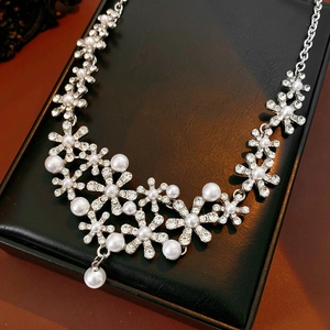Exquisite floral necklace with white pearls and sparkling crystals on a black display box