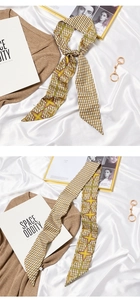 Detail of elegant yellow and green geometric print silk scarf tied as a stylish neck bow
