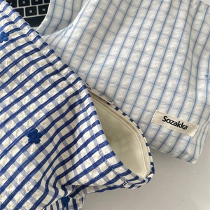 Vue détaillée des pochettes en tissu bleu à carreaux avec broderie et fermeture éclair