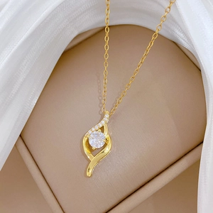 Close-up of gold S-curve necklace with zircon stones in a beige jewelry box