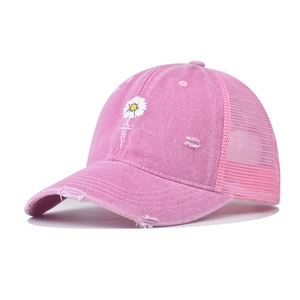 Detail of pink distressed trucker hat featuring daisy embroidery and breathable mesh back