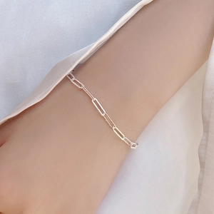 Detail of minimalist 925 sterling silver paperclip link bracelet on model's wrist