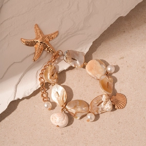Detailed close-up of ocean-style necklace with starfish, shells, and pearls on stones