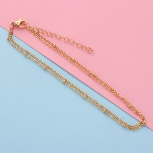 Detail of gold double-layer chain anklet with small beads, lobster clasp and extender