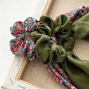 Detail of olive green satin and floral print fabric scrunchies on a wooden frame