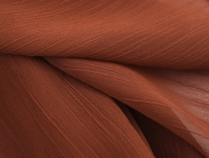 Vista macro de tela de gasa rojo óxido mostrando caída elegante y textura granulada