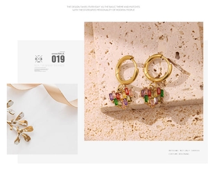 Vue détaillée des boucles d'oreilles cœur serties de zircons colorés et anneaux dorés