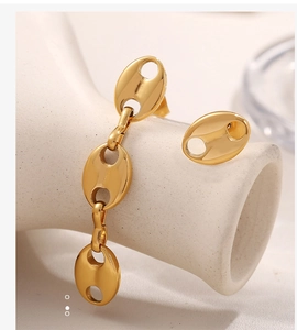Close-up of golden geometric pig nose chain earrings on white ceramic stand