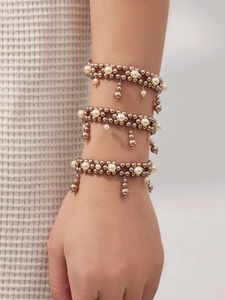 Detailed view of layered champagne gold beads and imitation pearl bracelets set