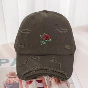 Detail of embroidered rose pattern and vintage distressed rips on a baseball cap