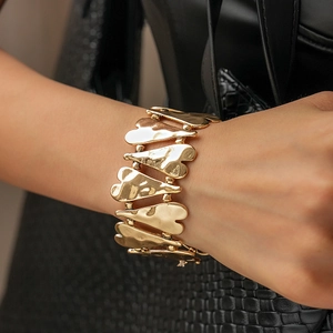 Détail d'un large bracelet doré à maillons cœur avec texture en métal martelé