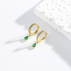 Detail of gold ear hoops with green teardrop pendants and micro-paved emerald zircons