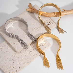 Détail de bracelets à pompons ouverts en or et argent sur un support en pierre et bois