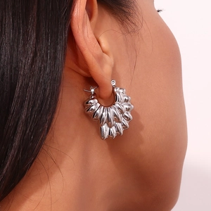 Macro shot of silver textured hoop earrings with double-layered hollow petal design on model