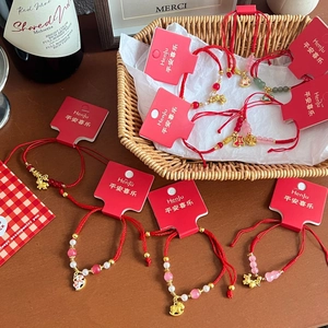 Detail of red woven bracelets with golden zodiac charms on Henju gift display cards