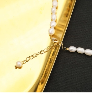 Macro view of freshwater pearl necklace with gold lobster clasp and heart extender